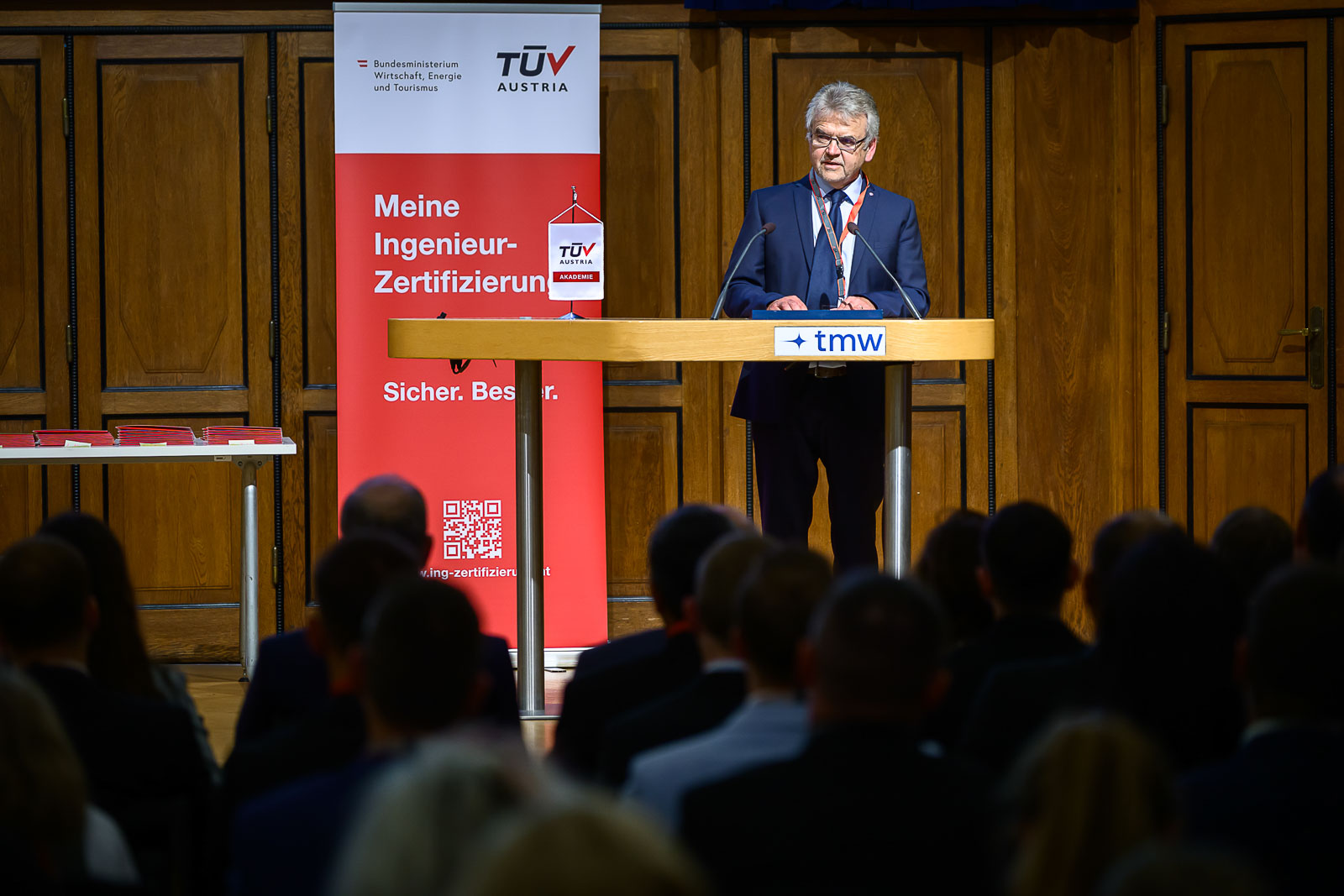 <br /> Mann im Anzug hält Rede auf Bühne.