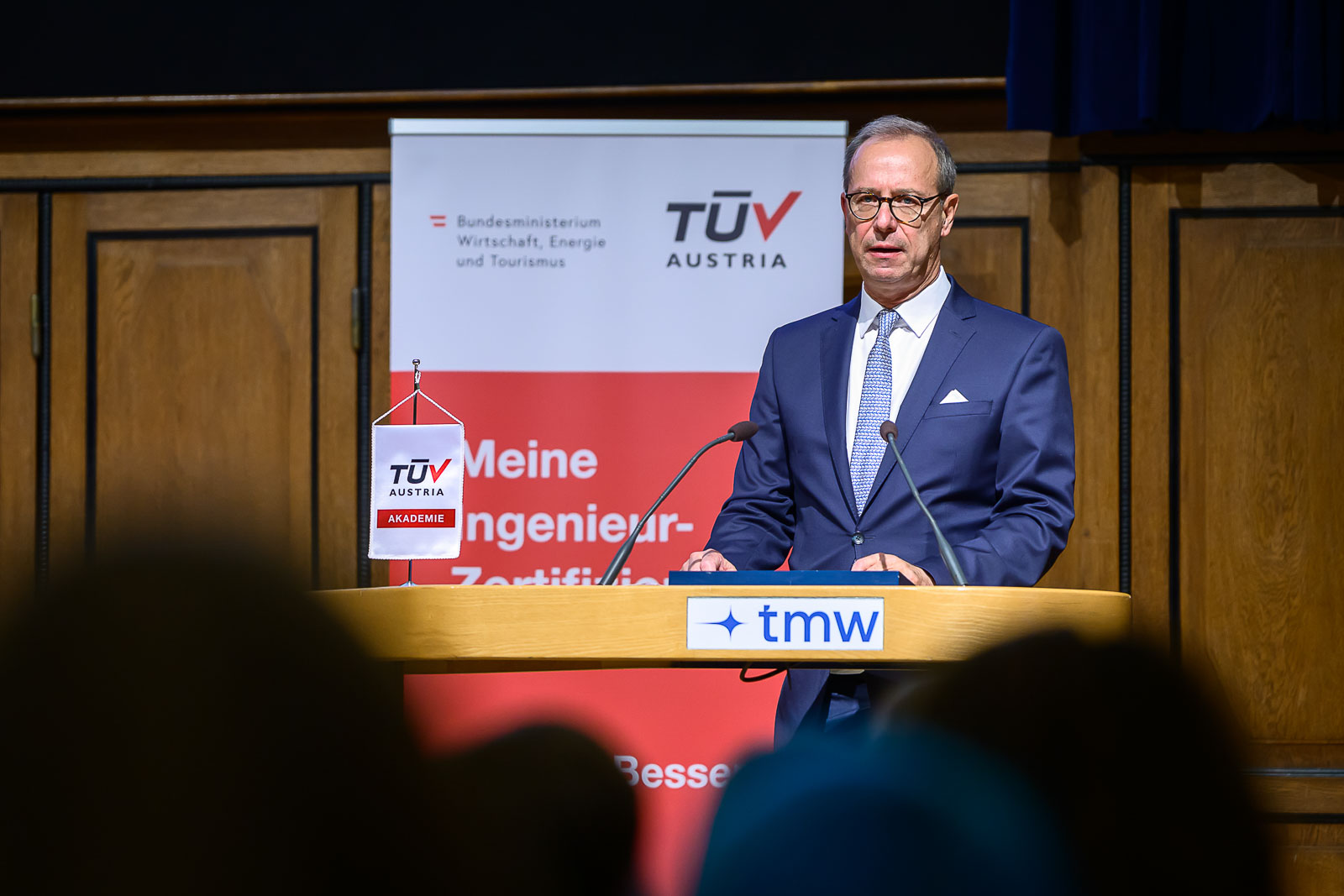 <br /> Mann im Anzug hält Rede auf Bühne.